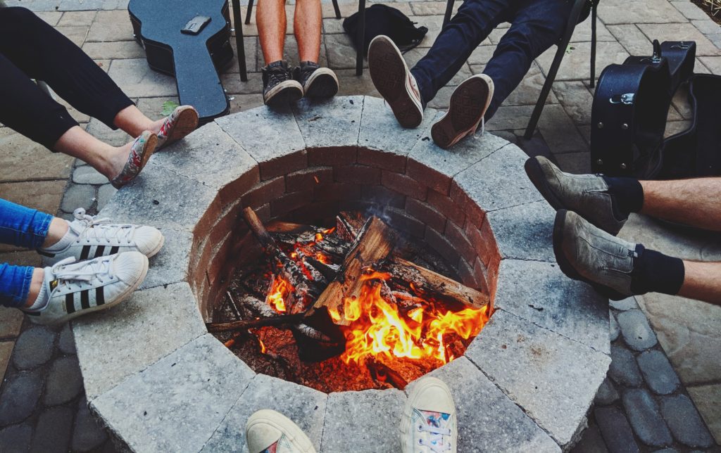 Friends sit by the fire in a BBQ party